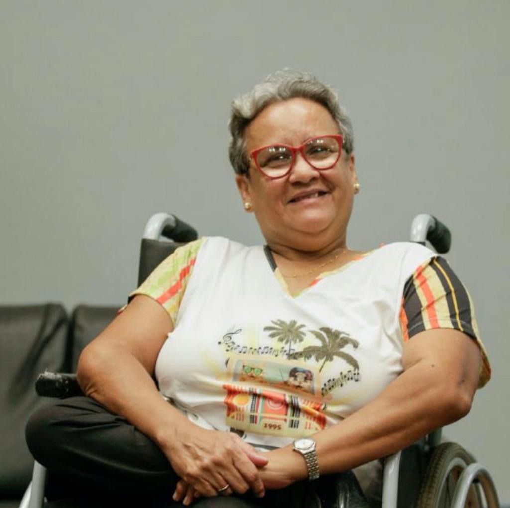 Foto de Arenilda sentada sorridente em sua cadeira de rodas Foto de Arenilda sentada sorridente em sua cadeira de rodas